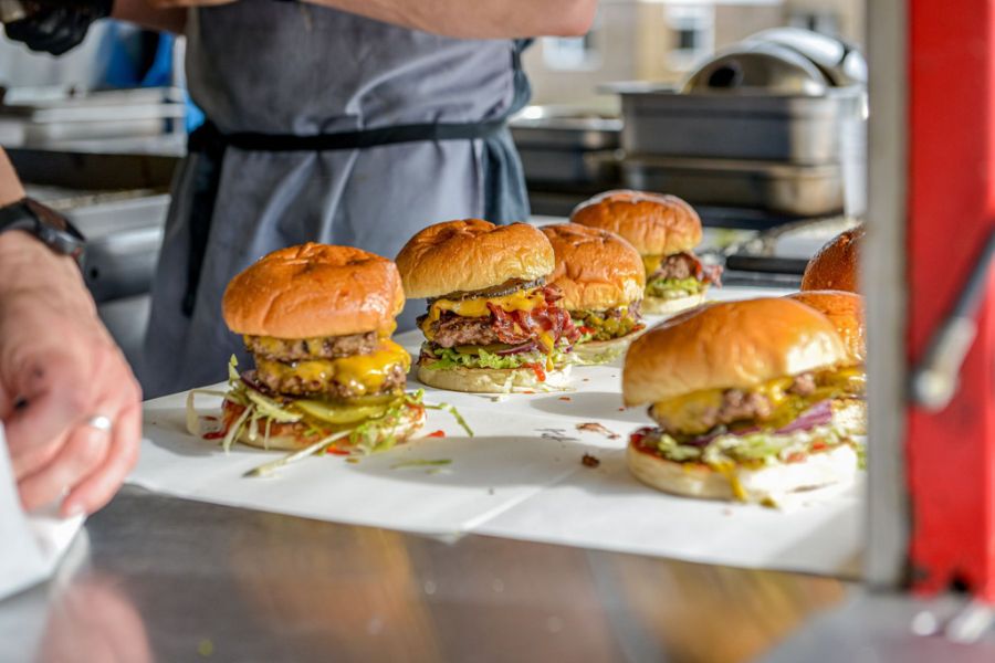 Tray of burgers in paper wrappers held by a chef at Steak & Honour, Cambridge